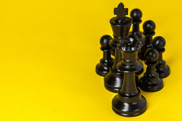 Chess figures on yellow background top view copy space