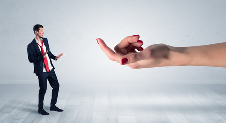Businessman with kisses on his face in an empty space where a big hand baiting him
