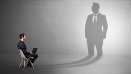 Fototapeta premium Skromny biznesmen zostaje i oferuje rzeczy ogromnemu cieńowi biznesmena