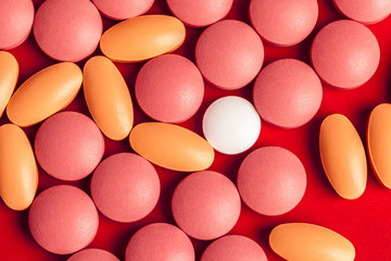 Many medicine pills close up on red background