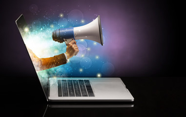 Hand with loudspeaker coming out of a laptop with sparkling effects
