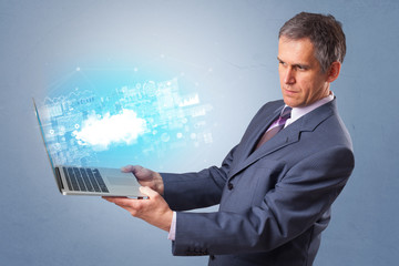 Man holding laptop projecting notifications, symbols and information based on cloud technology system
