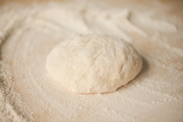 Ball of pizza dough on a rustic wooden background with dusting of flour