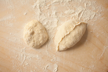 Raw homemade dough. Uncooked patty from yeast dough with stuffing are lying on a wooden plank and ready for baking.