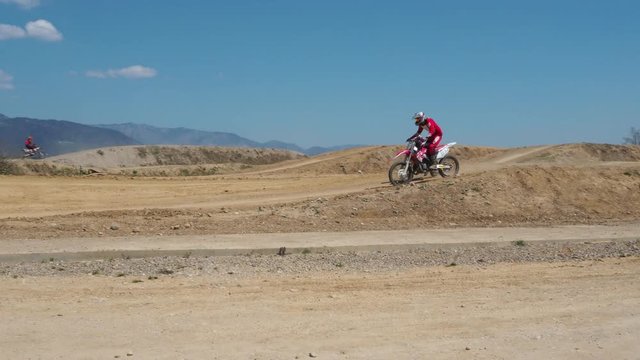 Motocross training of old and young bikers riding together on a dirt track.