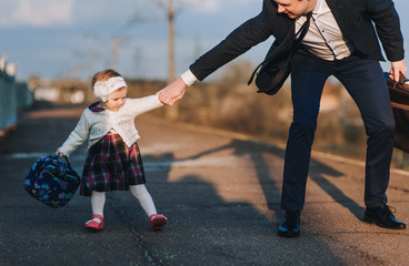 A loving father does not want to part with his little daughter, leaving on a trip to work, holding his hand. Farewell and parting. The last meeting of loving people. Life style.