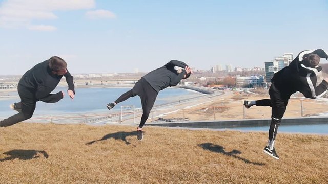 Three young men doing acrobatic tricks on the grass
