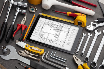 Tablet with construction tools and blueprint concept
