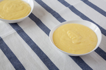 Homemade vanilla custard pudding in white bowls, side view.