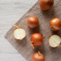 Unpeeled raw yellow onions on a white wooden background, top view. Flat lay, flat lay, from above.