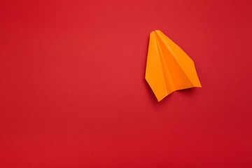Flat lay of colour paper plane on red background with text space.
