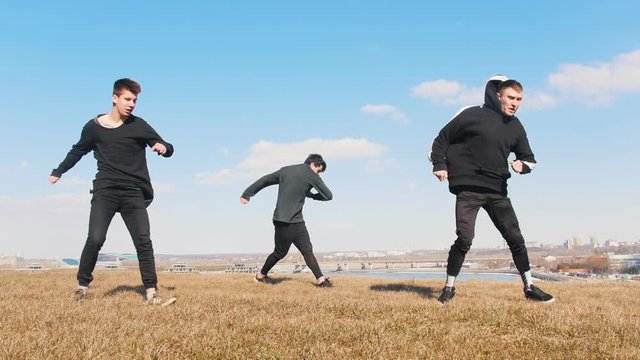 Three young men synchronously performing acrobatic flip on the grass