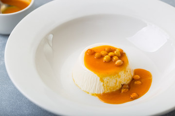 dessert pana cotta with see-buckthorn orange sauce in white plate restaurant