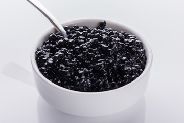 black caviar in a bowl on a white acrylic background