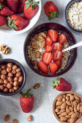 Oat flakes with nuts-almonds,hazelnuts and strawberries in a bowl with a spoon for Breakfast top view