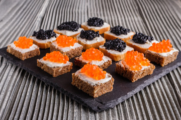 Snack with red and black caviar on a stone plate