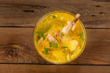 Bouillon quail egg in a transparent round plate on a wooden background