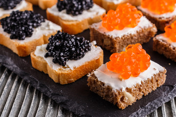 Snack with red and black caviar on a stone plate