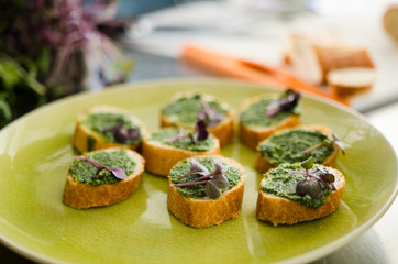 Delicious vegan sandwiches with fresh bread and pea paste garnished with herbs served on a green plate.