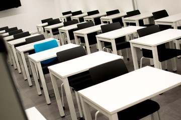 Classroom with black chairs and one blue chair. Hiring, vacant or choosing concept
