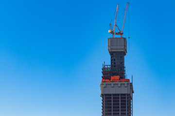 Construction of high-rise building with cranes against the blue sky