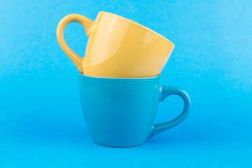 Two empty cups, yellow and blue, on a blue background