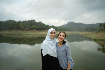 Fototapeta premium asian and muslim middle eastern woman friend together smiling to camera