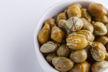 Pickled capers on a white acrylic background