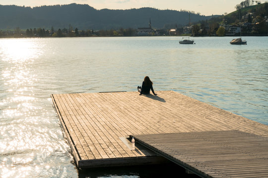 silhouette of a woman relaxing on a floating dock on a lake at sunset