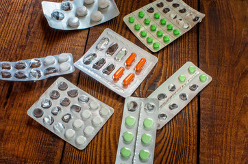 different pills in packs on wooden background