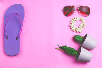 Beach purple flip flops, aviator sunglasses, seashell bracelet and succulent cacti cactus on a pink background. Summer vacation colorful travel beach flat lay with free copy space for text