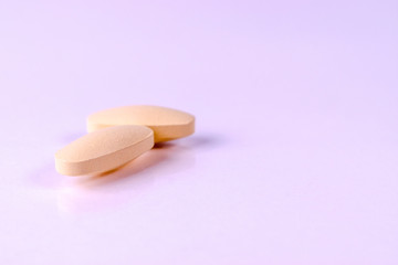 Close-up two calcium or Vitamin and mineral pills tablets isolated on white paper background. Copy space for advertisers.