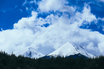 Mountain snow peak, beautiful natural winter backdrop. Ice top of the hill, blue sky background. Alpine forest landscape.