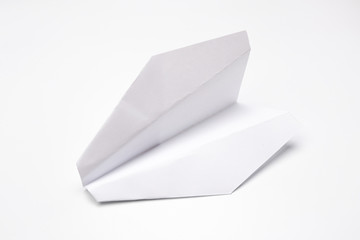 Flat lay of white paper plane on white background.