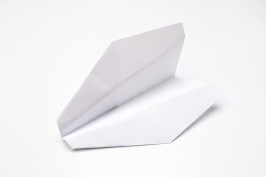 Flat lay of white paper plane on white background.