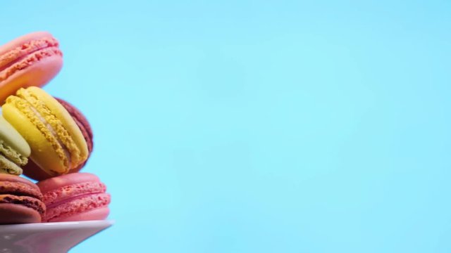 Sweet color macaroons on blue background. Slide from left to right