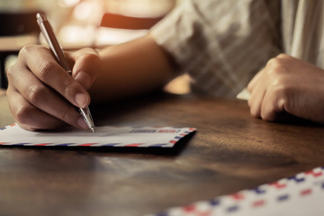 hand using a black pen writing on the letter paper .Retro instagram style filter photo with sunset...