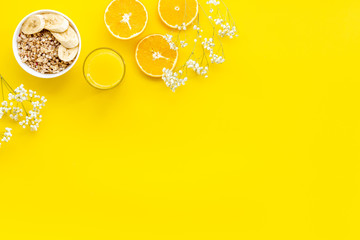 food for healthy breakfast with granola and fresh orange juice on bright yellow background top view mock up