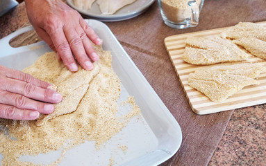 Breaded fish filets with eggs. Freshness on the table with wooden chopping board and salt