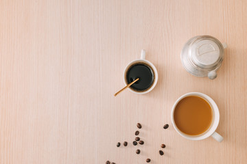 Cups of coffee with coffee beans and vietnamese Phin filter on wooden background