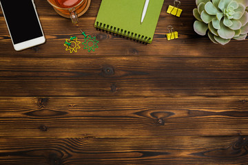 Top view business office desk.notebook,pencil,tea cup ,plant ,mobile phone,paperclips on wooden table background