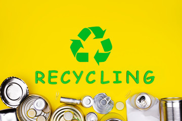 Aluminum metal reusable tin cans bottle caps in garbage recycling sign symbol Save nature pollution contamination ecology environmental problem damage concept Secondary raw materials yellow background