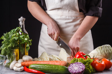 young woman in a gray apron cut cabbage