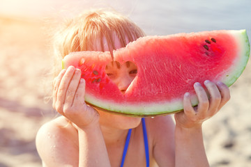 Little girl eating watermelon on the beach