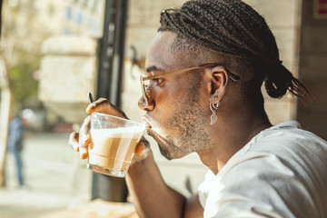 Handsome young African American drinking coffee with milk