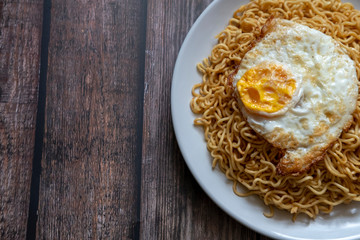 Fried curly noodle with fried egg on top of wooden table ready to be served.