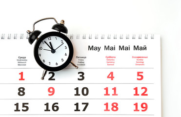 concept of calendar holidays in may. alarm clock and Calendar for may, schedule of days with working days and holidays. May calendar page with months and dates. close up, top view