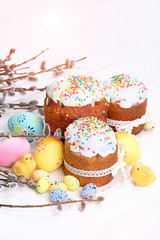 Beautiful Easter composition with Easter cakes, orthodox sweet bread - kulich and willow twigs, painted eggs, chickens on light background. Easter holiday scene. copy space
