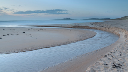 View of steam through Embleton Beach, Northumberland, England, in blue hour light, with...