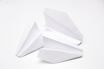 Flat lay of white paper planes on white background.